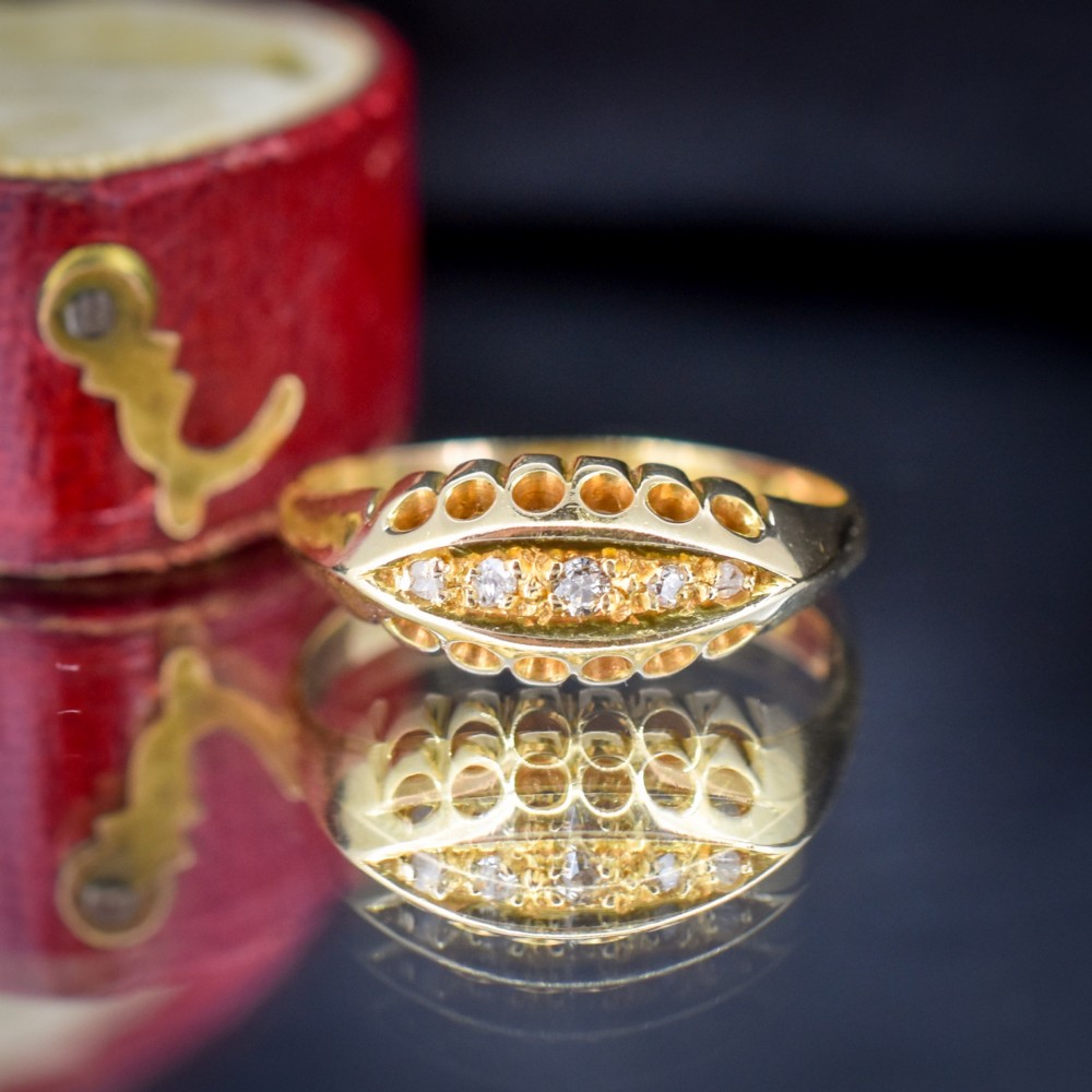 An 18ct yellow gold boat ring set with five graduated diamonds within a carved pierced gallery. View V