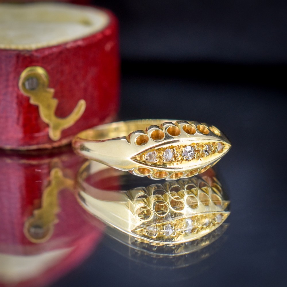An 18ct yellow gold boat ring set with five graduated diamonds within a carved pierced gallery. View VI