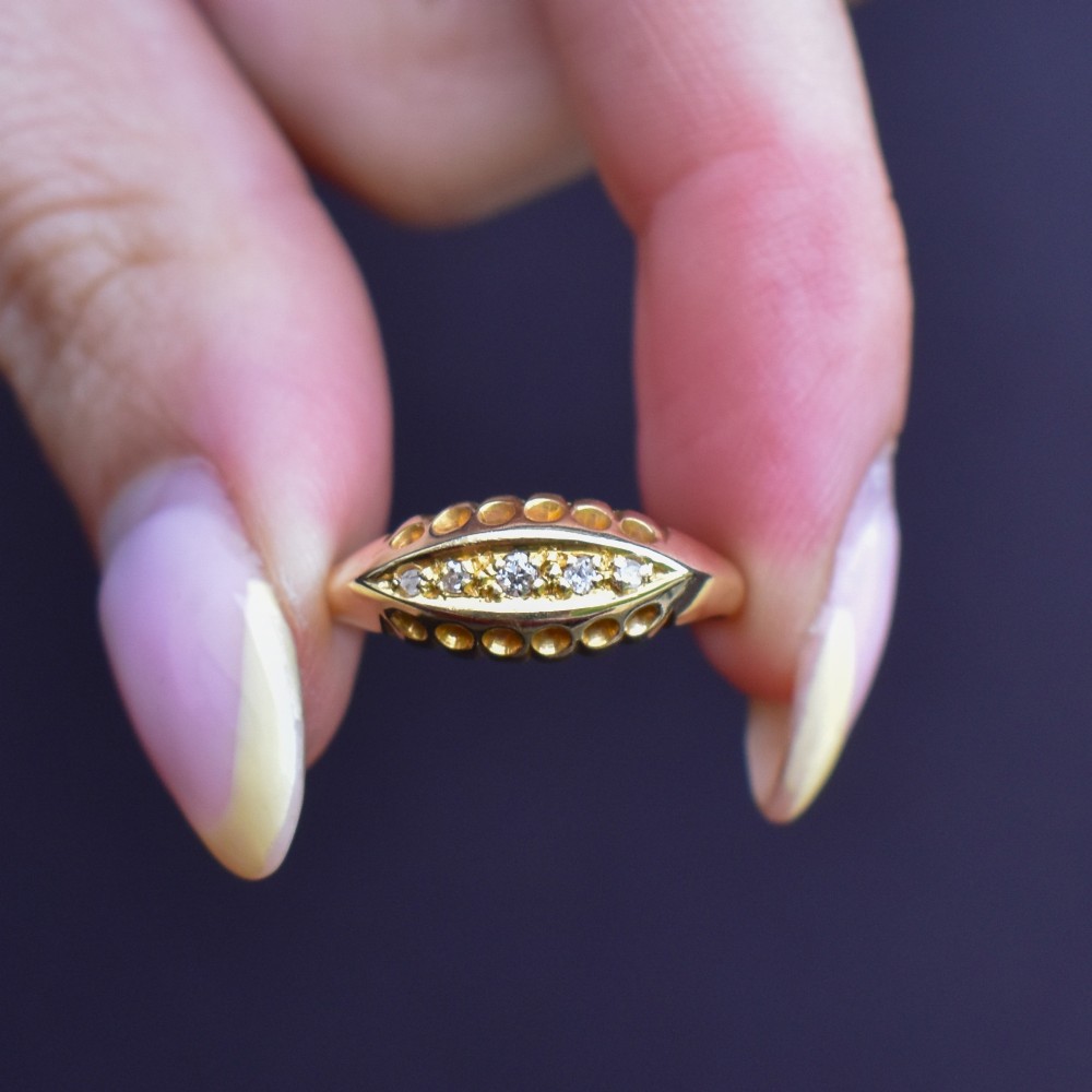 An 18ct yellow gold boat ring set with five graduated diamonds within a carved pierced gallery. View IX