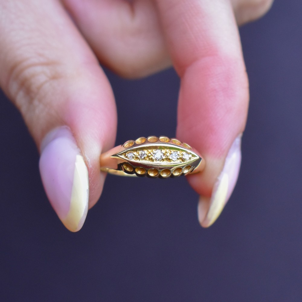An 18ct yellow gold boat ring set with five graduated diamonds within a carved pierced gallery. View X