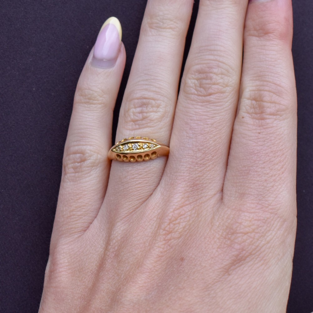 An 18ct yellow gold boat ring set with five graduated diamonds within a carved pierced gallery. View XI
