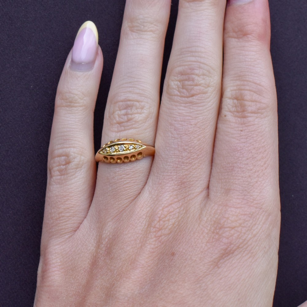 An 18ct yellow gold boat ring set with five graduated diamonds within a carved pierced gallery. View XII