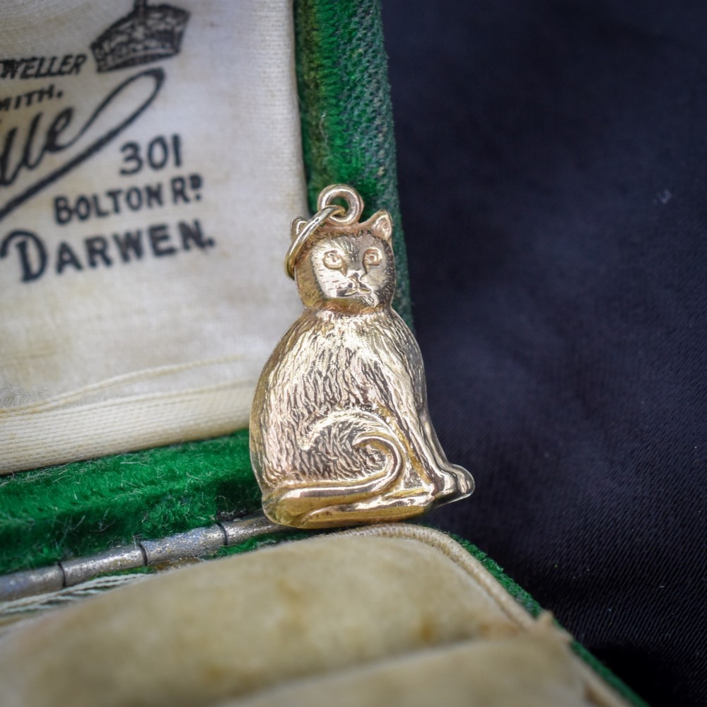 A small 9ct yellow gold charm shaped as a seated cat with engraved fur texture and a loop at the top for suspension. View II