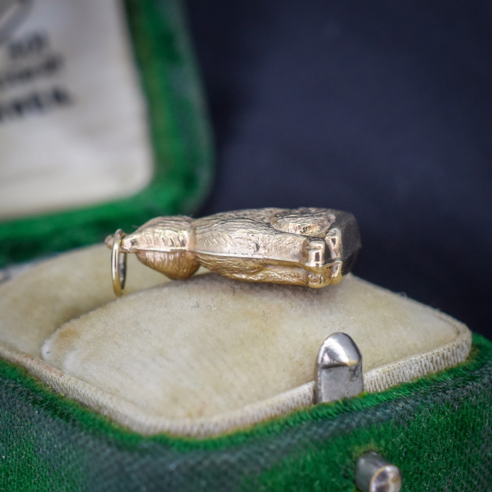 A small 9ct yellow gold charm shaped as a seated cat with engraved fur texture and a loop at the top for suspension. View V