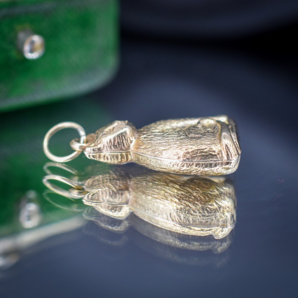 A small 9ct yellow gold charm shaped as a seated cat with engraved fur texture and a loop at the top for suspension. View VII