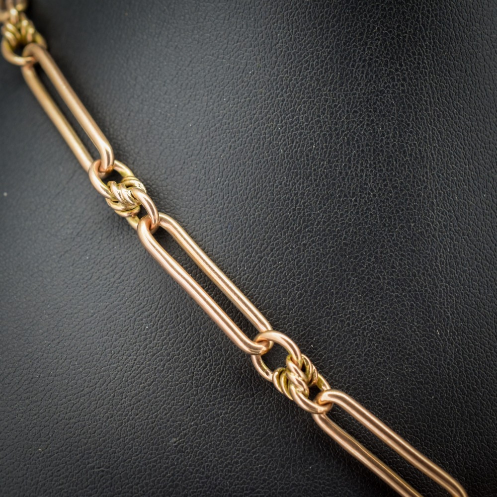 An antique 9ct yellow gold necklace featuring elongated trombone links, twisted love knots, and a central suspended T-bar. View III