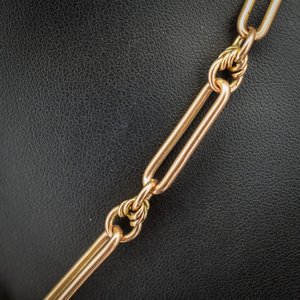 An antique 9ct yellow gold necklace featuring elongated trombone links, twisted love knots, and a central suspended T-bar. View IV