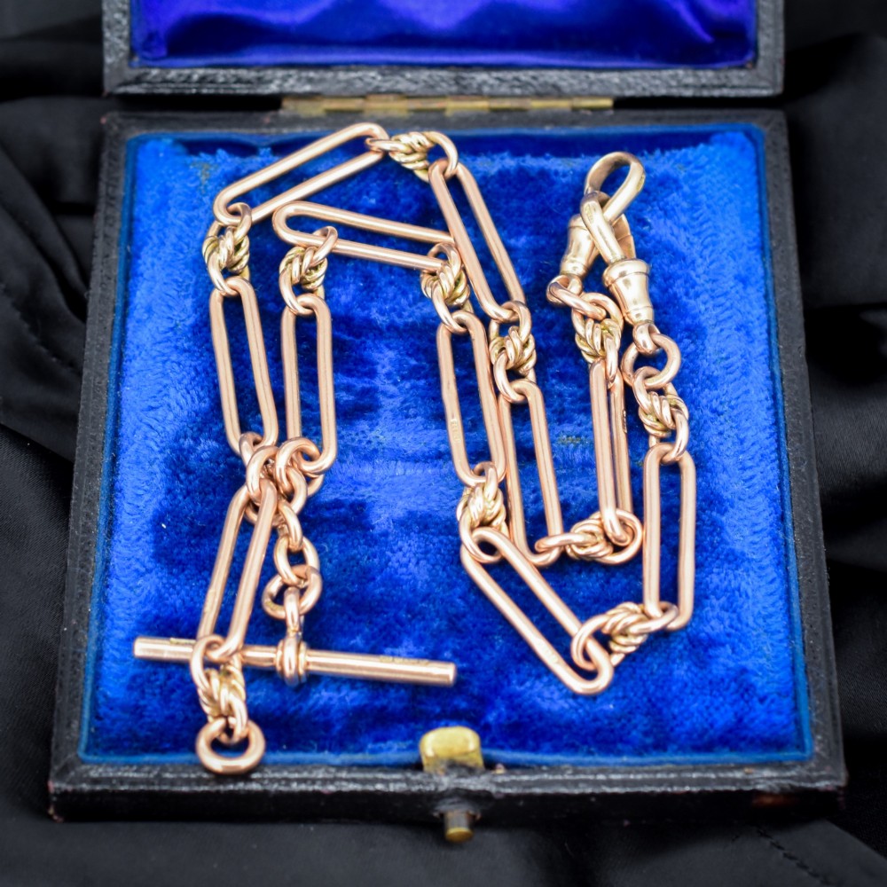 An antique 9ct yellow gold necklace featuring elongated trombone links, twisted love knots, and a central suspended T-bar. View VI