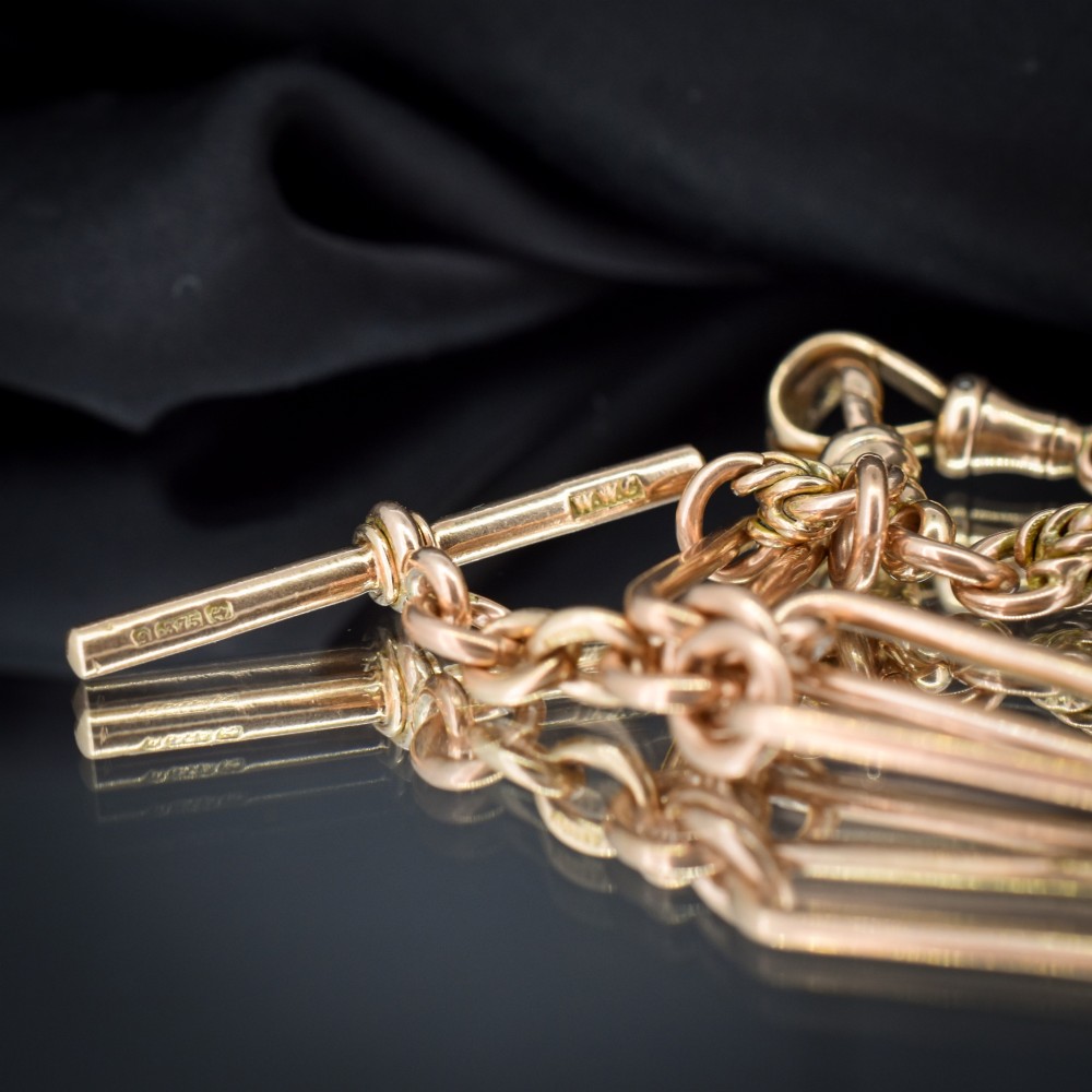 An antique 9ct yellow gold necklace featuring elongated trombone links, twisted love knots, and a central suspended T-bar. View VII