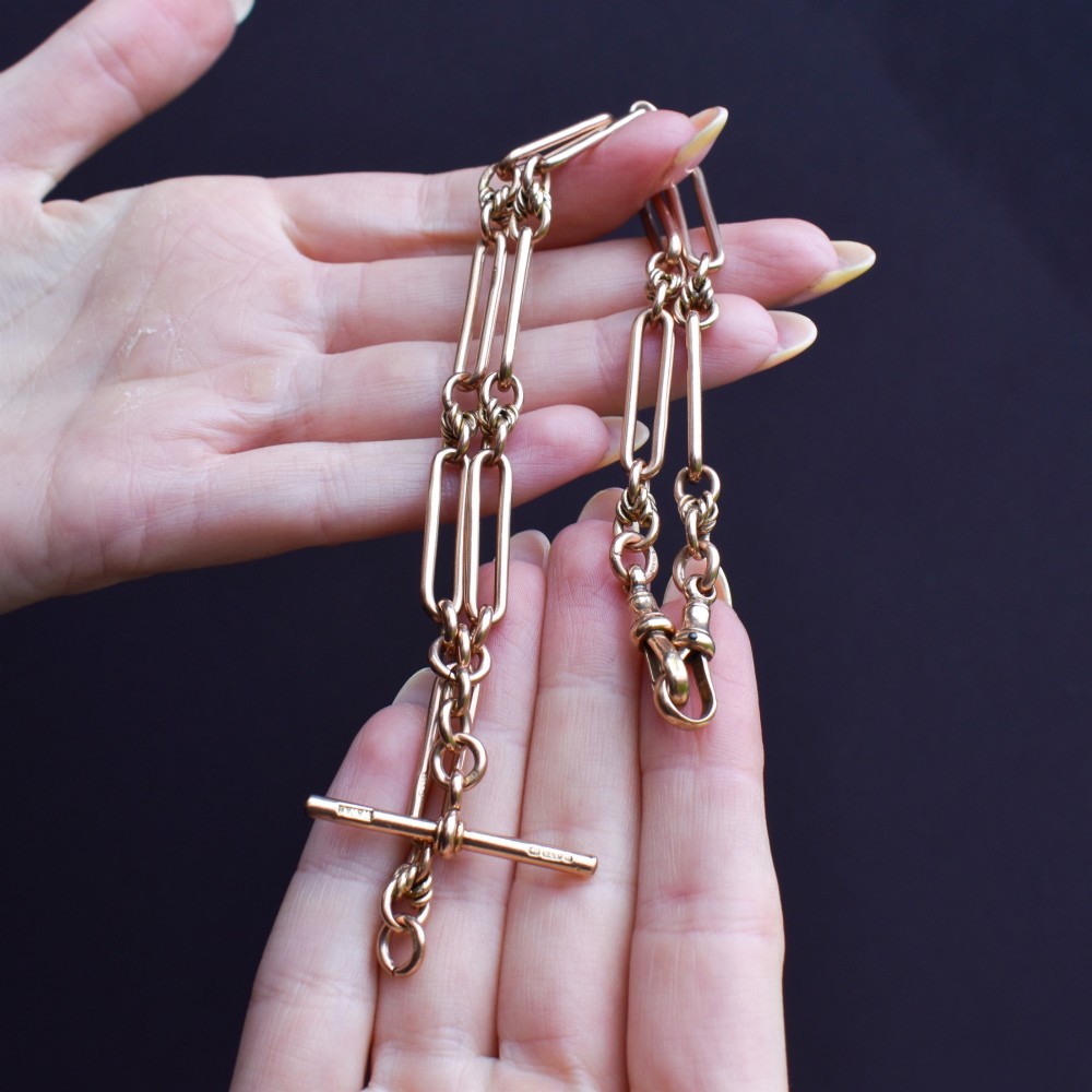 An antique 9ct yellow gold necklace featuring elongated trombone links, twisted love knots, and a central suspended T-bar. View IX