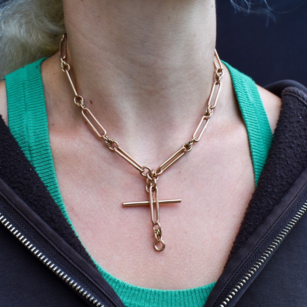 An antique 9ct yellow gold necklace featuring elongated trombone links, twisted love knots, and a central suspended T-bar. View XII