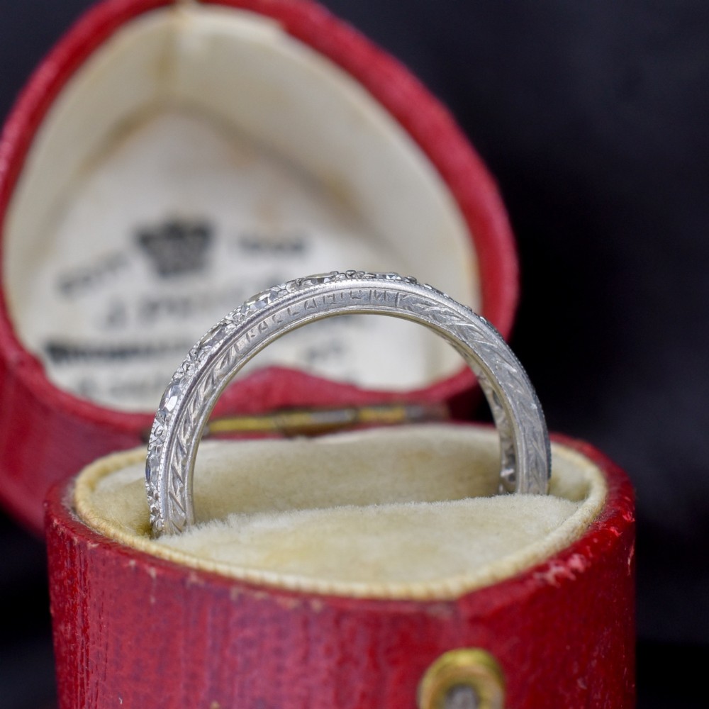 An Art Deco palladium full eternity ring set with a continuous band of round diamonds bordered by milgrain edging. View IV