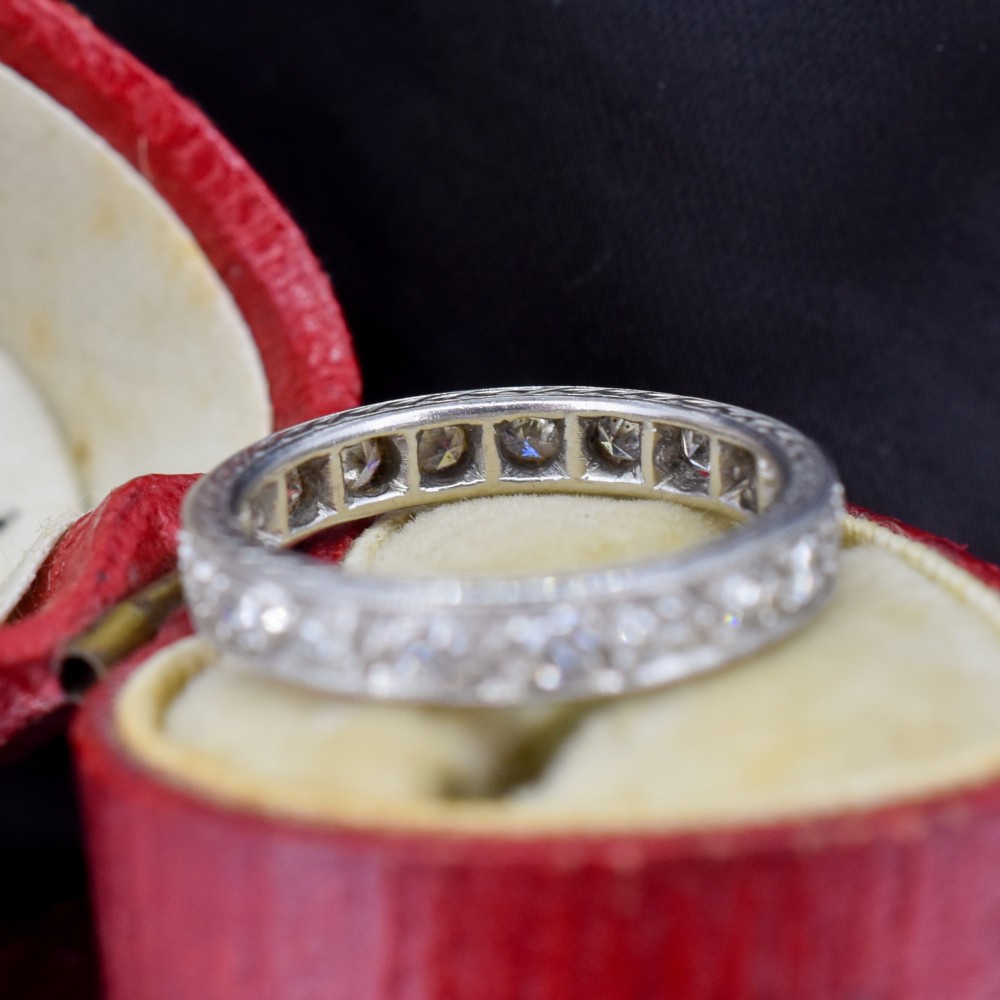 An Art Deco palladium full eternity ring set with a continuous band of round diamonds bordered by milgrain edging. View V