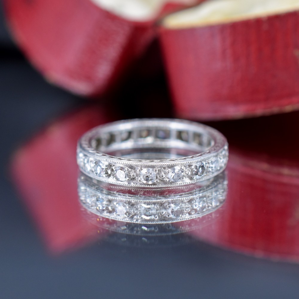 An Art Deco palladium full eternity ring set with a continuous band of round diamonds bordered by milgrain edging. View VI