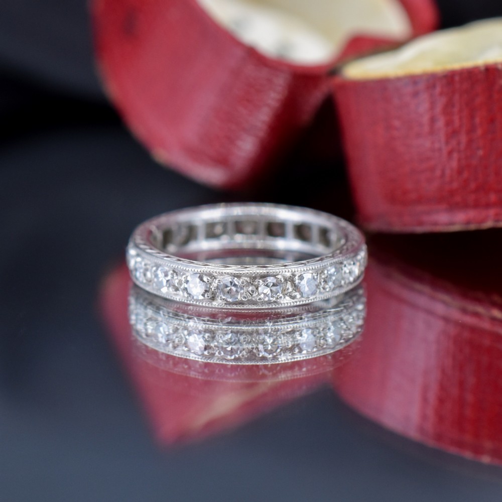 An Art Deco palladium full eternity ring set with a continuous band of round diamonds bordered by milgrain edging. View VII