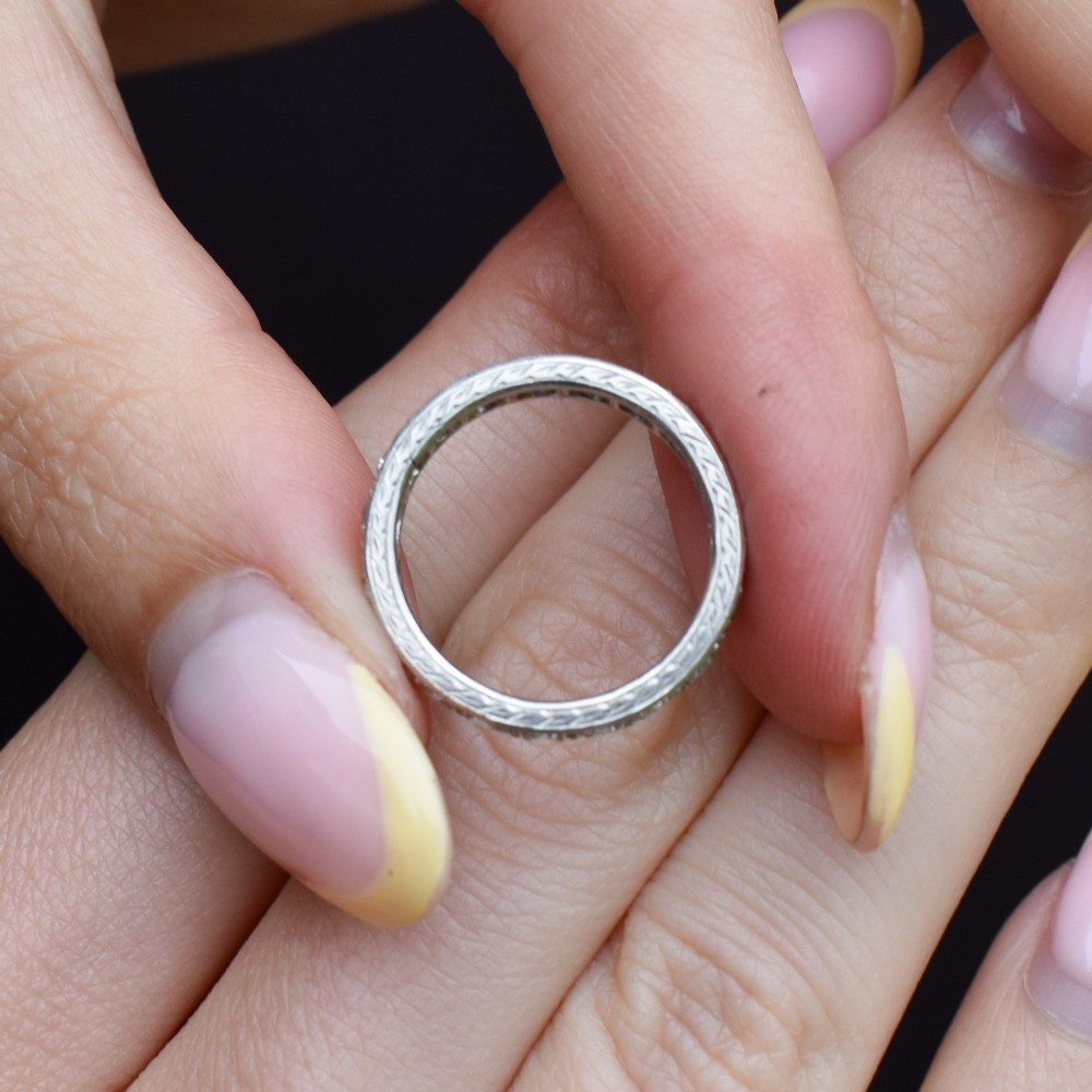 An Art Deco palladium full eternity ring set with a continuous band of round diamonds bordered by milgrain edging. View IX
