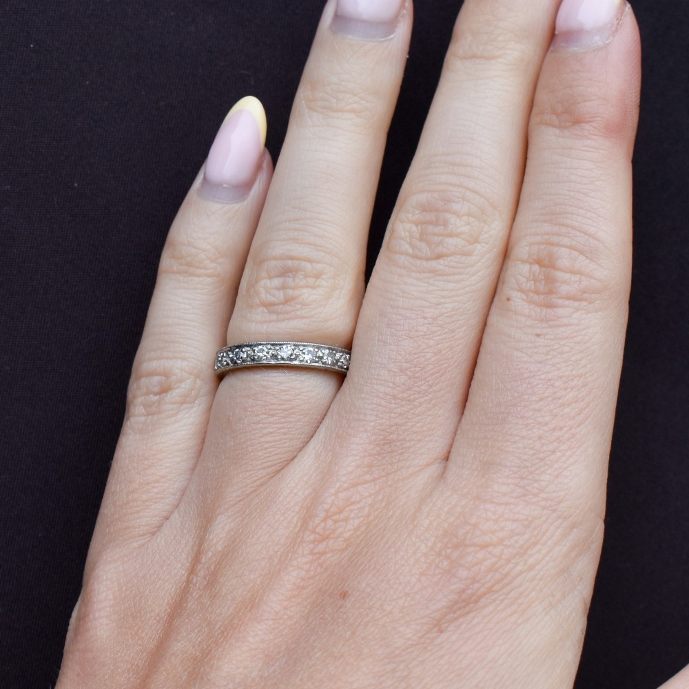 An Art Deco palladium full eternity ring set with a continuous band of round diamonds bordered by milgrain edging. View X