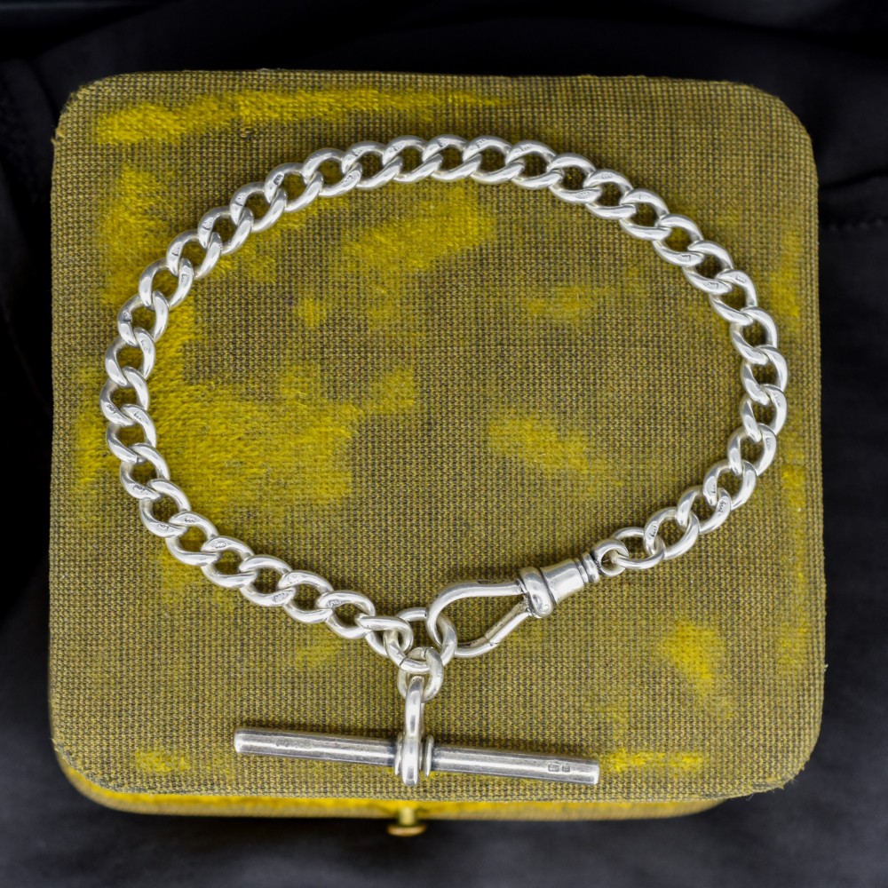 A sterling silver curb link chain bracelet featuring a swivel dog clip fastener and a T-bar pendant.