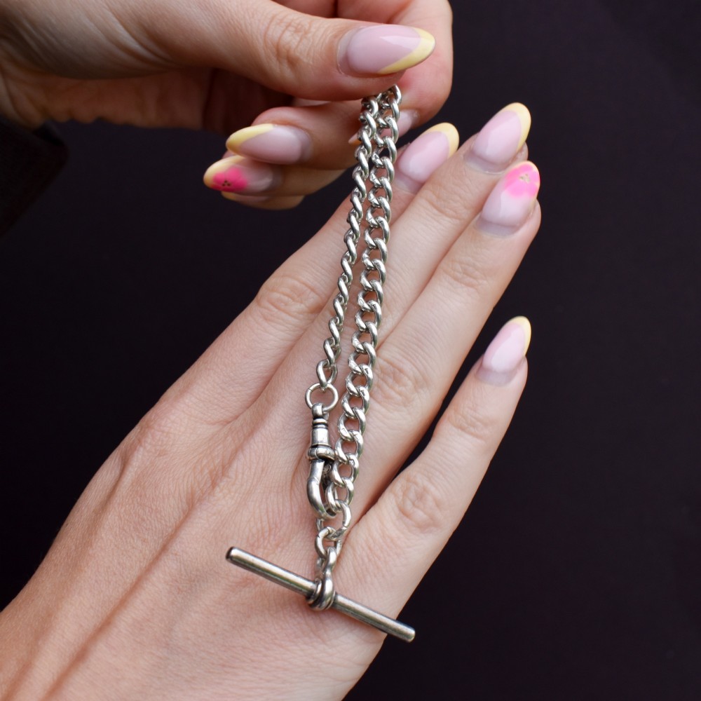 A sterling silver curb link chain bracelet featuring a swivel dog clip fastener and a T-bar pendant. View IX