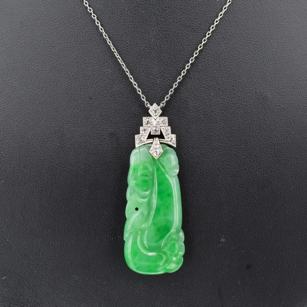 An Art Deco carved green jade pendant with geometric platinum and diamond accents on a chain. View II
