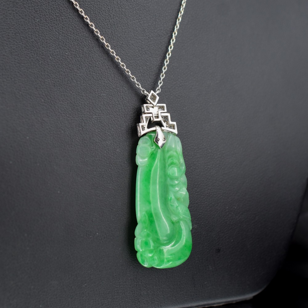 An Art Deco carved green jade pendant with geometric platinum and diamond accents on a chain. View V