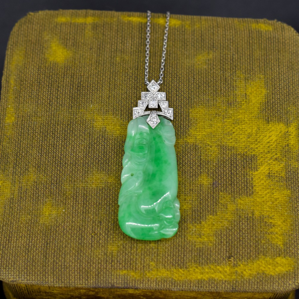 An Art Deco carved green jade pendant with geometric platinum and diamond accents on a chain. View VI