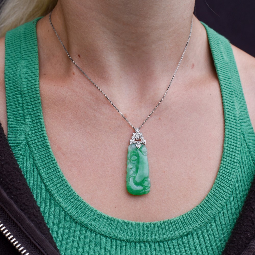 An Art Deco carved green jade pendant with geometric platinum and diamond accents on a chain. View XII