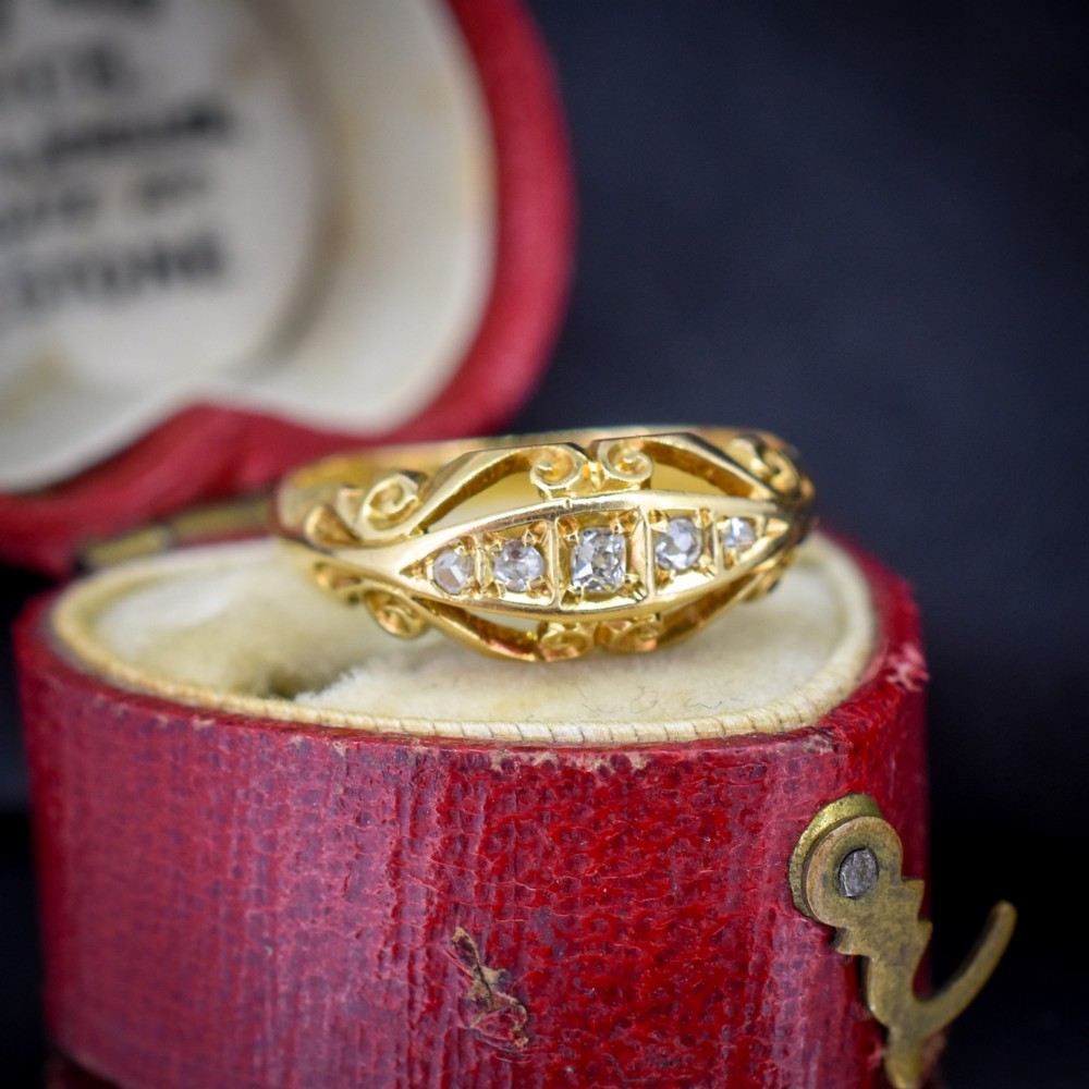 An 18ct yellow gold boat-shaped ring set with five graduated diamonds and featuring carved scrollwork along the gallery. View II