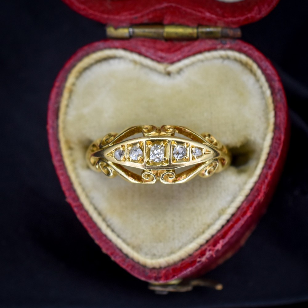 An 18ct yellow gold boat-shaped ring set with five graduated diamonds and featuring carved scrollwork along the gallery. View III