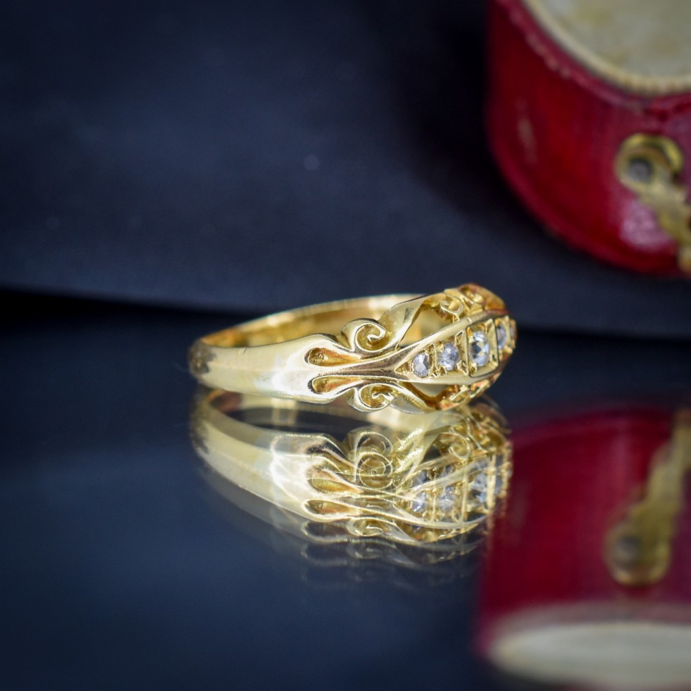 An 18ct yellow gold boat-shaped ring set with five graduated diamonds and featuring carved scrollwork along the gallery. View IV