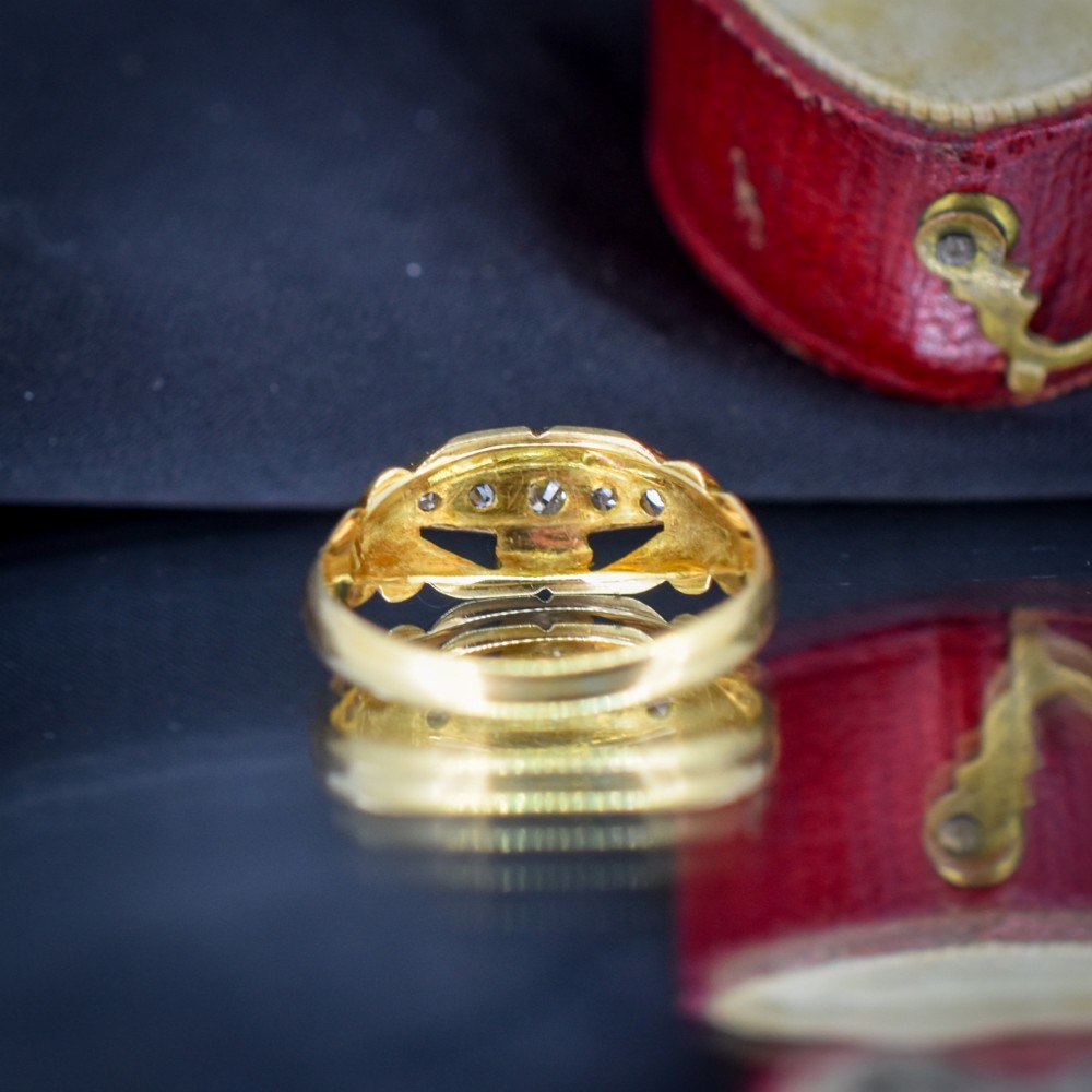 An 18ct yellow gold boat-shaped ring set with five graduated diamonds and featuring carved scrollwork along the gallery. View V
