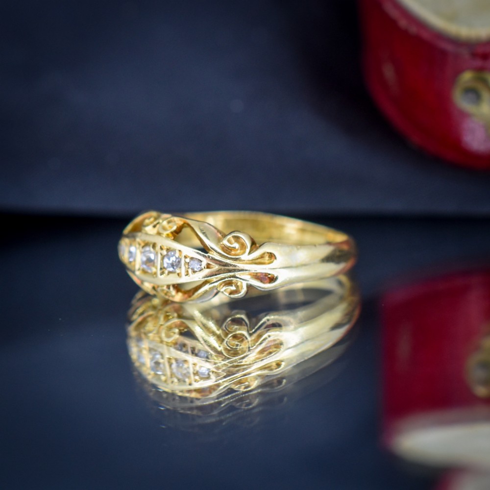 An 18ct yellow gold boat-shaped ring set with five graduated diamonds and featuring carved scrollwork along the gallery. View VI
