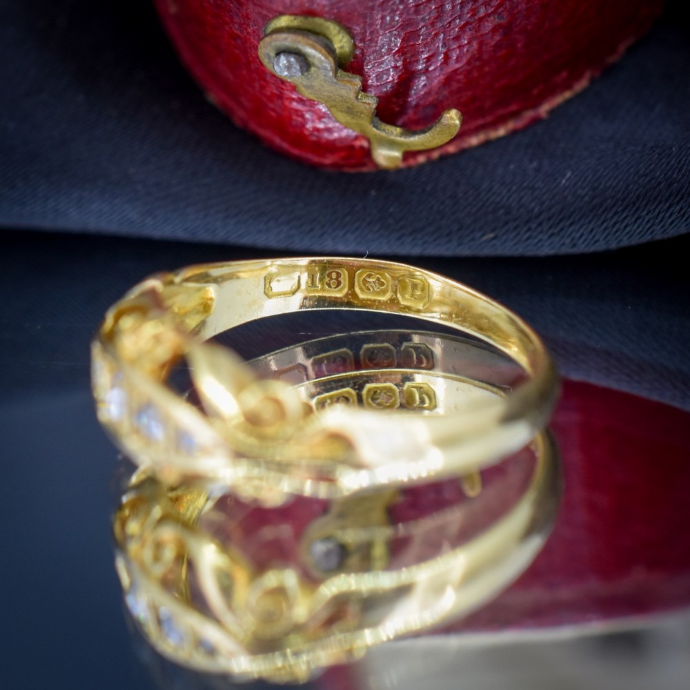 An 18ct yellow gold boat-shaped ring set with five graduated diamonds and featuring carved scrollwork along the gallery. View VII