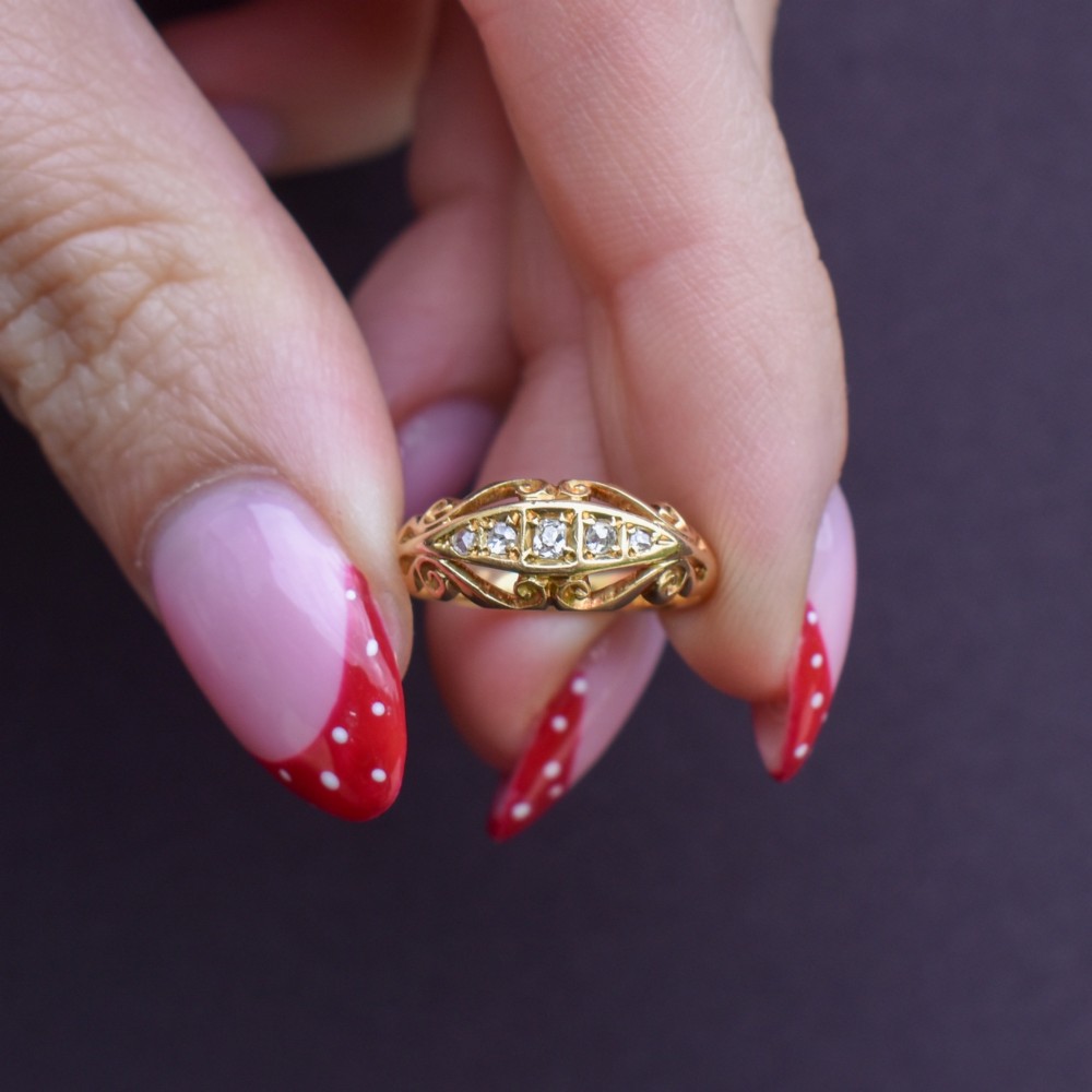 An 18ct yellow gold boat-shaped ring set with five graduated diamonds and featuring carved scrollwork along the gallery. View VIII
