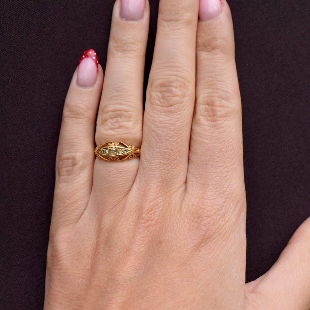 An 18ct yellow gold boat-shaped ring set with five graduated diamonds and featuring carved scrollwork along the gallery. View X