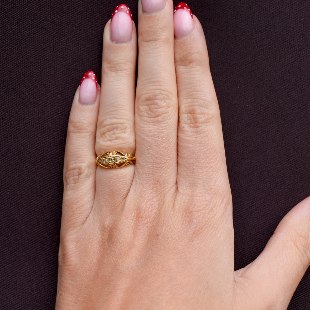 An 18ct yellow gold boat-shaped ring set with five graduated diamonds and featuring carved scrollwork along the gallery. View XI