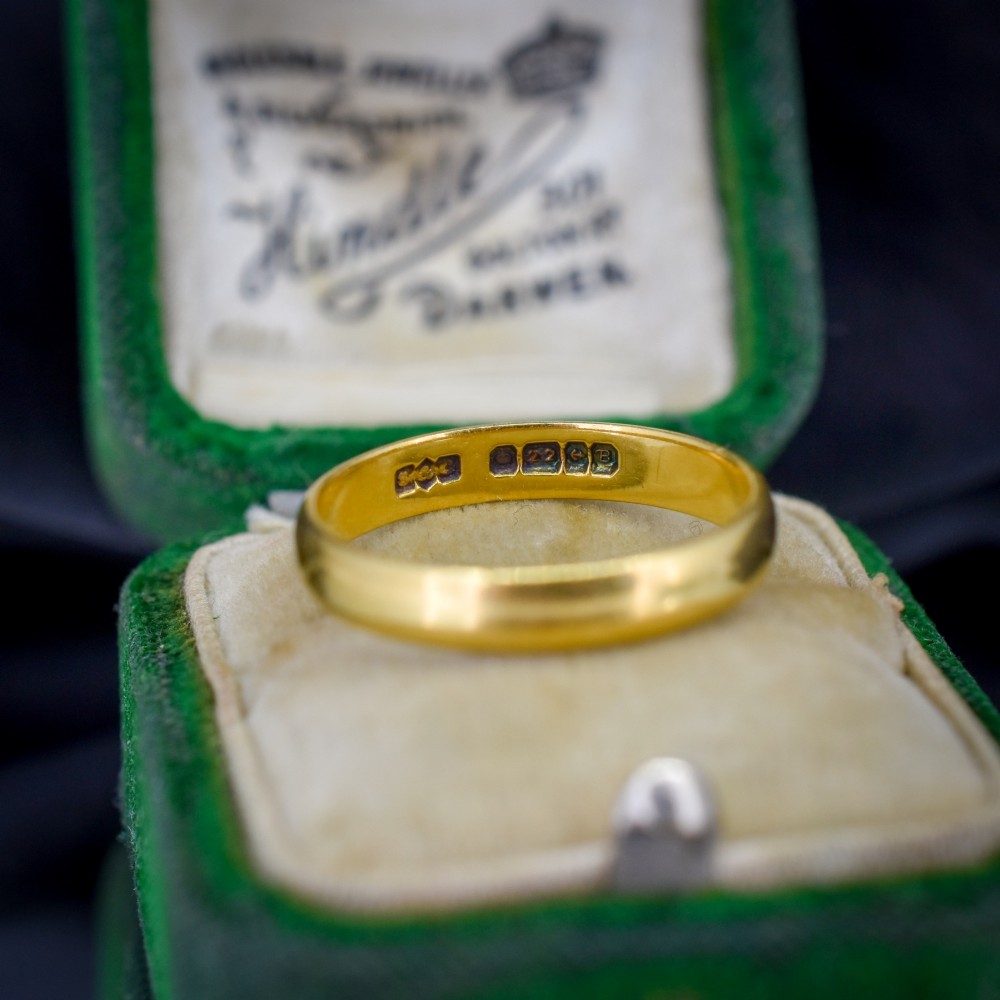 A polished 22ct yellow gold plain wedding band displaying visible interior hallmarks.