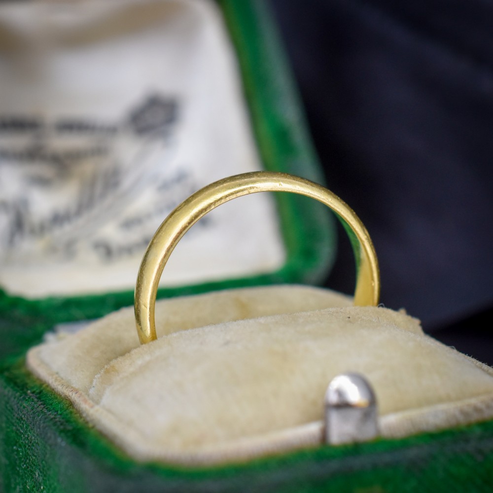 A polished 22ct yellow gold plain wedding band displaying visible interior hallmarks. View IV
