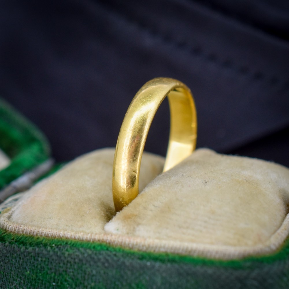 A polished 22ct yellow gold plain wedding band displaying visible interior hallmarks. View V