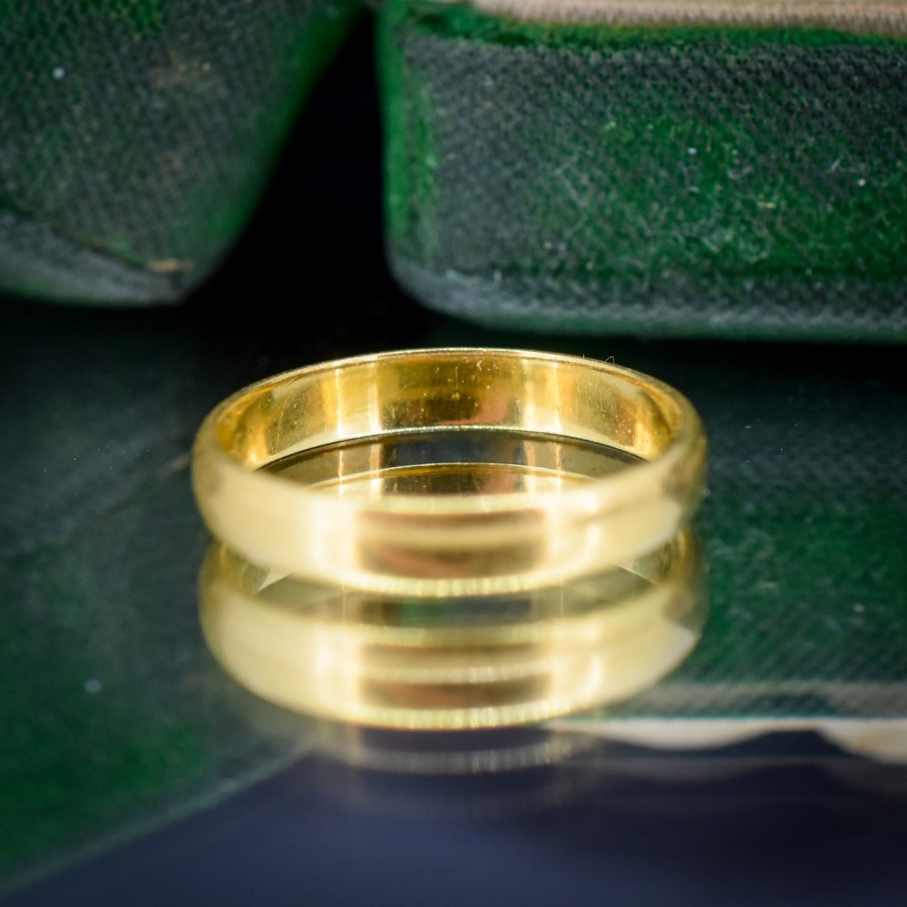 A polished 22ct yellow gold plain wedding band displaying visible interior hallmarks. View VI