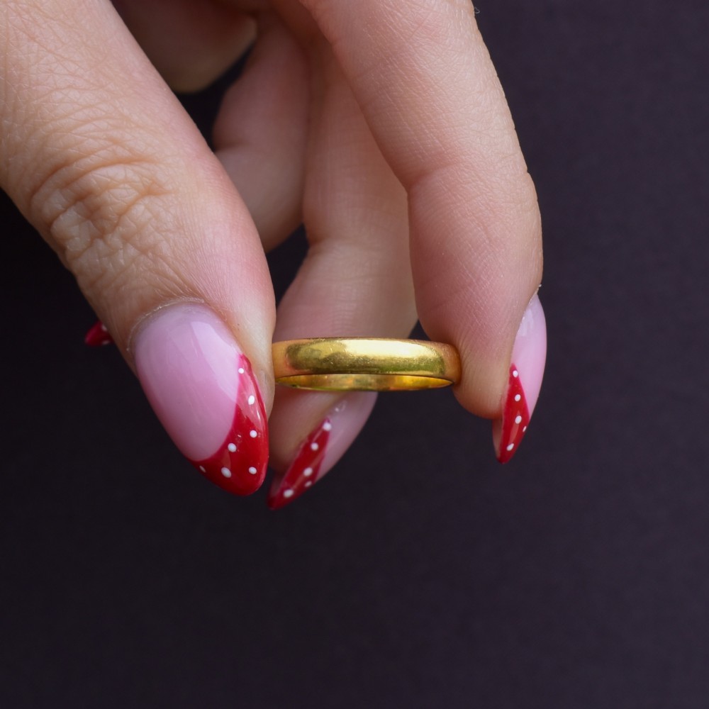 A polished 22ct yellow gold plain wedding band displaying visible interior hallmarks. View VII