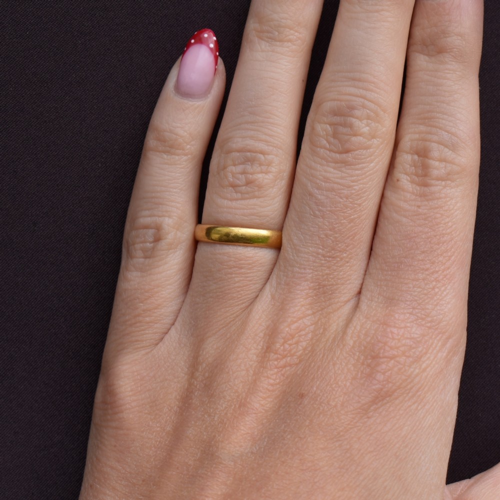 A polished 22ct yellow gold plain wedding band displaying visible interior hallmarks. View IX