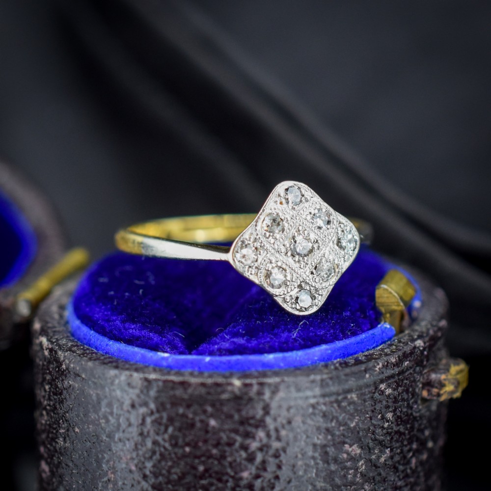 An Art Deco 18ct yellow gold ring featuring a platinum square lozenge cluster set with multiple diamonds and fine millegrain details.