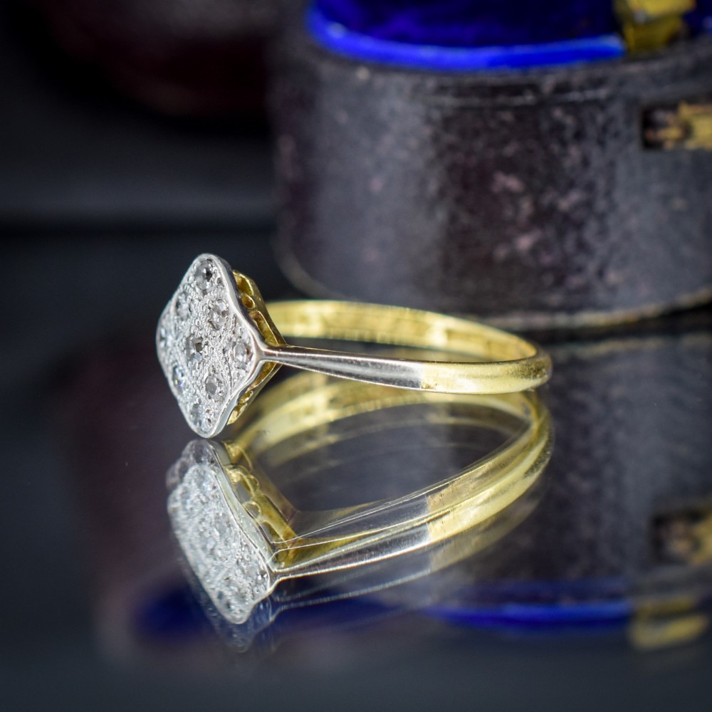 An Art Deco 18ct yellow gold ring featuring a platinum square lozenge cluster set with multiple diamonds and fine millegrain details. View V