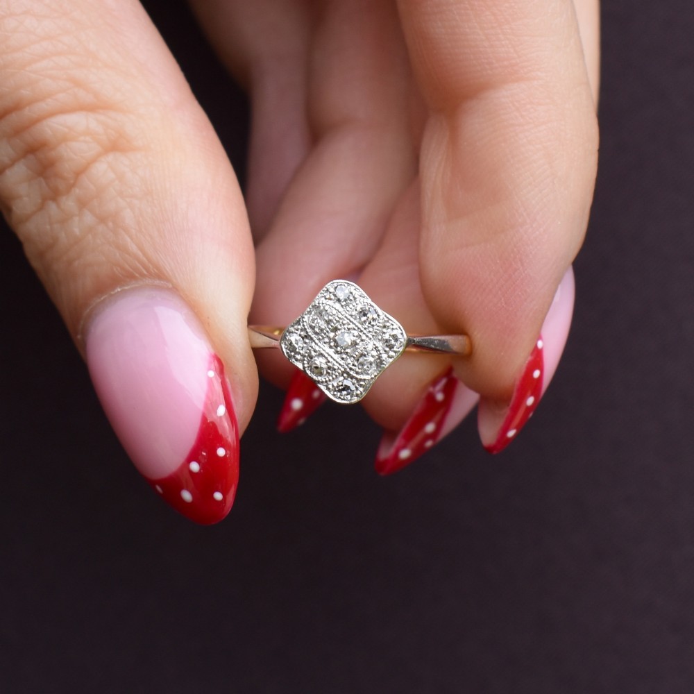 An Art Deco 18ct yellow gold ring featuring a platinum square lozenge cluster set with multiple diamonds and fine millegrain details. View IX