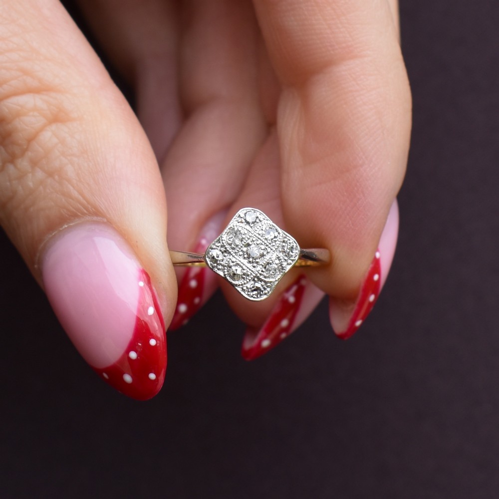 An Art Deco 18ct yellow gold ring featuring a platinum square lozenge cluster set with multiple diamonds and fine millegrain details. View X