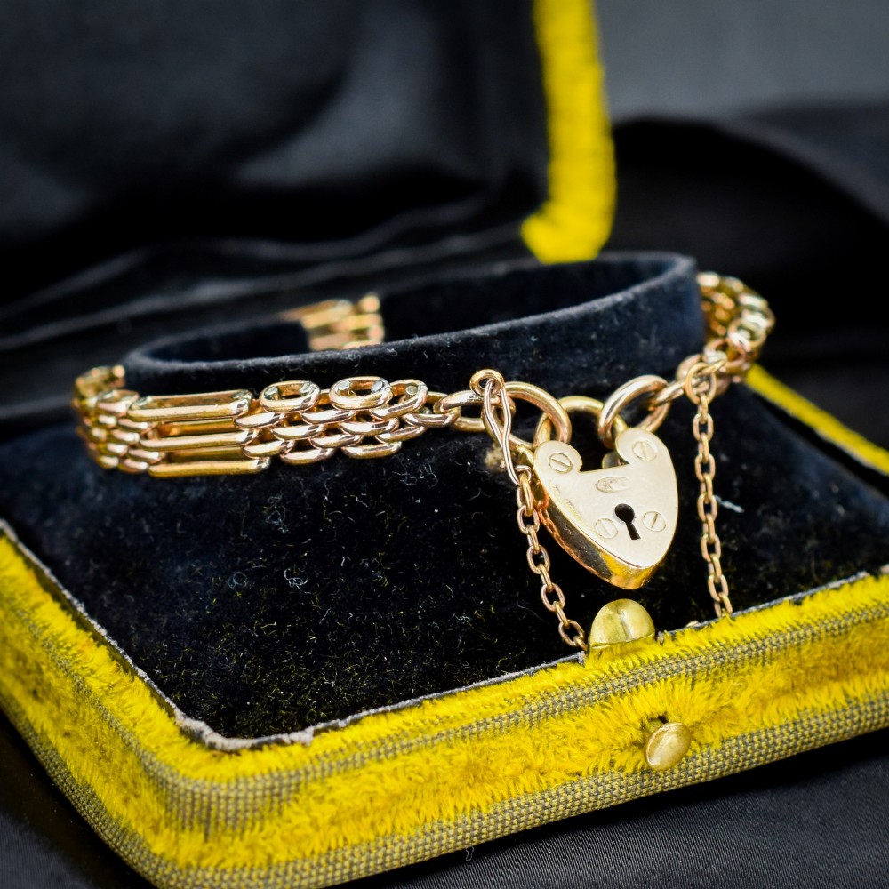 An antique rolled gold gate link bracelet featuring an engraved heart-shaped padlock clasp and safety chain. View II