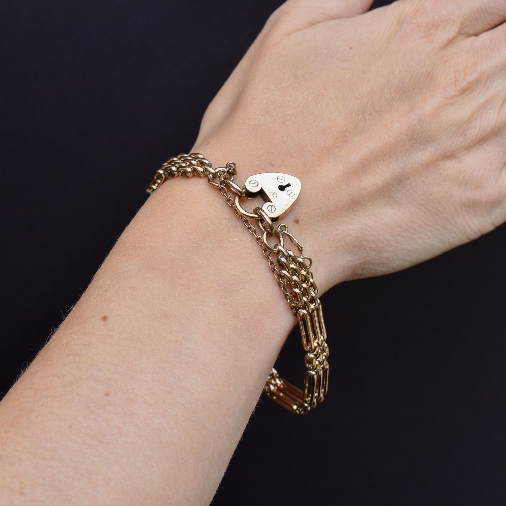 An antique rolled gold gate link bracelet featuring an engraved heart-shaped padlock clasp and safety chain. View VIII