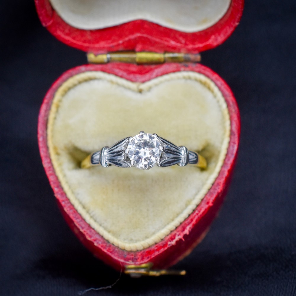 An Art Deco diamond solitaire ring featuring a round cut diamond set between detailed, fan-etched shoulders on an 18ct yellow gold band.