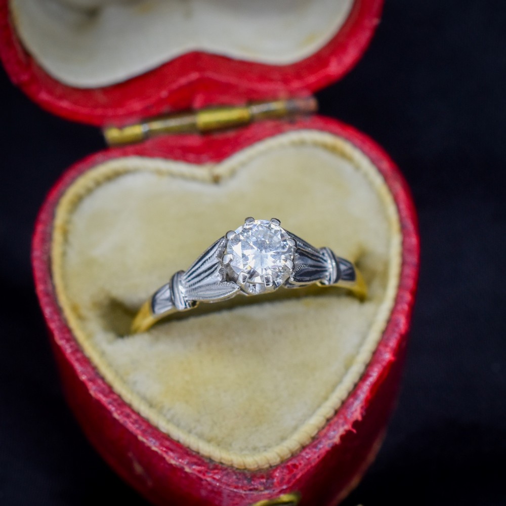 An Art Deco diamond solitaire ring featuring a round cut diamond set between detailed, fan-etched shoulders on an 18ct yellow gold band. View IV